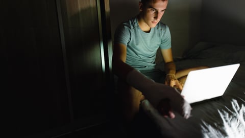 Adolescent travaillant la nuit sur un ordinateur portable