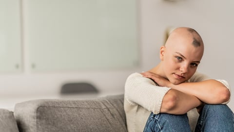 Une jeune femme assise sur un divan est atteinte d'alopécie ou de pelade.