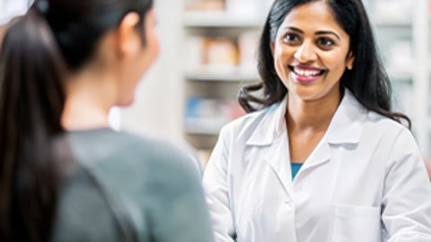 une pharmacienne sourit à un patient au comptoir de la pharmacie