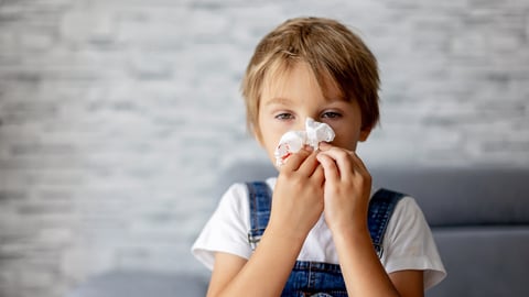 Un enfant saigne du nez et tient un mouchoir sur ses narines