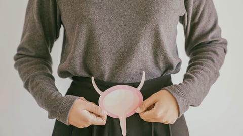 Une femme tient devant son ventre une représentation d'une vessie.