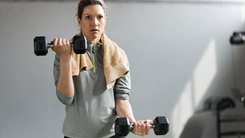 Une jeune femme soulève des poids lors d'un entraînement de musculation