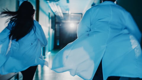 Deux médecins de dos courent dans un couloir d'hôpital