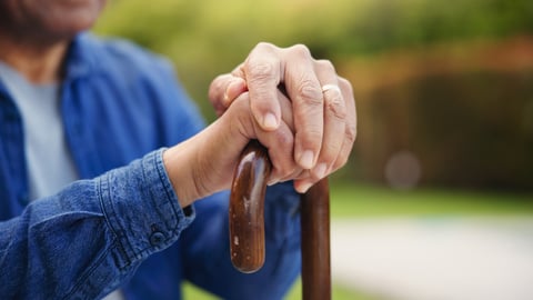 Mains d'une femme âgée reposant sur sa canne