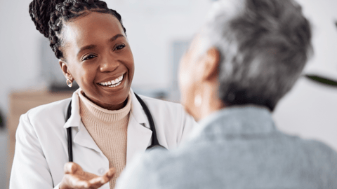Une femme médecin souriante parle à un patient dans un cabinet médical.