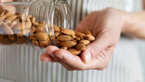 Une personne prend une pleine poignée d'amandes