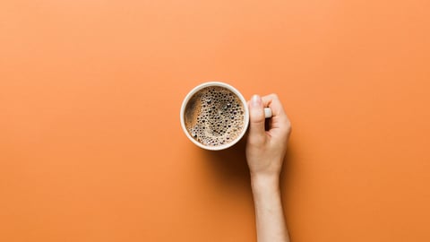 Une main tient une tasse de café