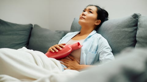 Une femme a placé une bouillotte sur son ventre en raison de douleurs.