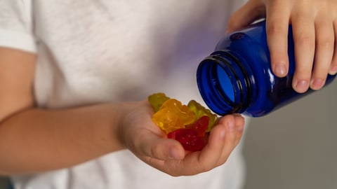 Un enfant prend une poignée d'oursons en gelée d'une boite ronde
