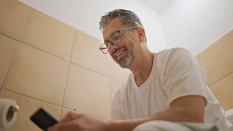Homme qui consulte son téléphone aux toilettes