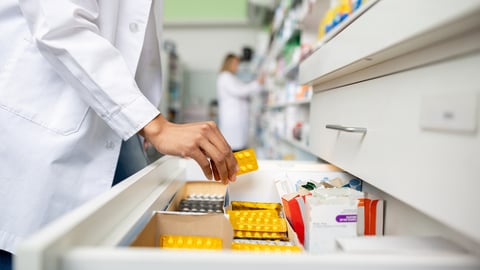 Une pharmacienne sort une tablette de pilules d'un tiroir