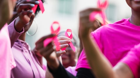 Plusieurs femmes vêtues de rose tiennent des rubans roses pour le cancer du sein.
