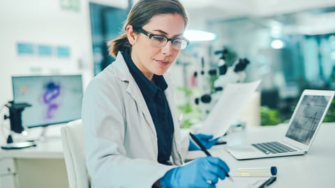 Chercheuse dans son labo qui prend des notes