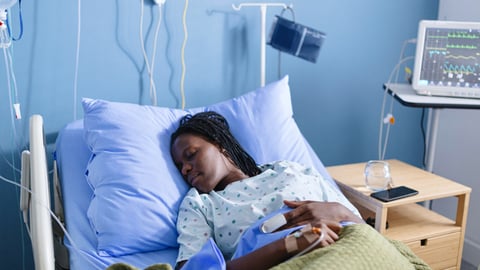 Une femme noire hospitalisée dort dans un lit d'hôpital.