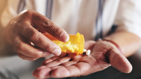 Une personne âgée verse des pilules dans sa main.