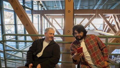 Deux inconnus discutent en regardant un cellulaire.