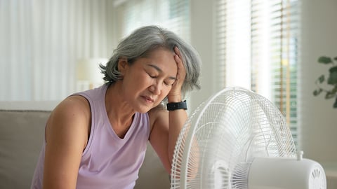 Femme devant un ventilateur, l'air fatigué.