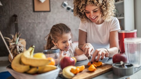 Une femme et sa fille coupent des fruits. Crédit photo: zeljkosantrac/ Getty Images