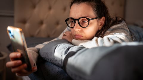 Femme déprimée sur son cellulaire. Crédit photo: Nikola Stojadinovic/ Getty Images 
