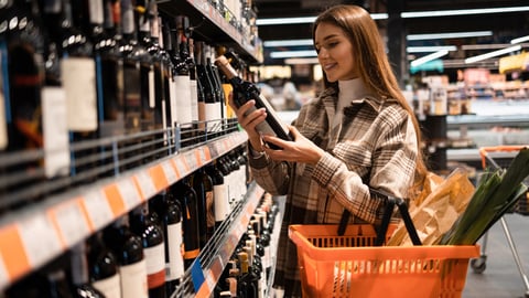 Une jeune femme regarde les informations nutritionnelles d'une bouteille d'alcool. Crédit photo: Andrii Borodai/ Getty Images