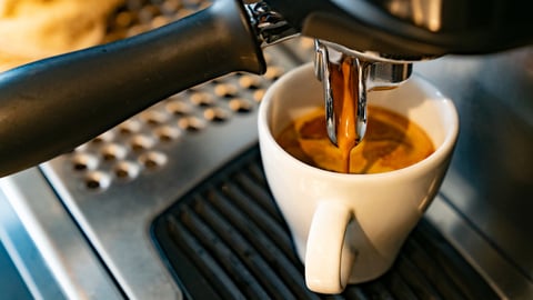 Une machine à espresso fait couler un café dans une petite tasse.