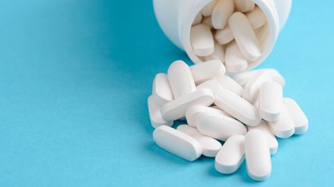 Un pot de médicament, sous la forme de pilules longues et blanches.