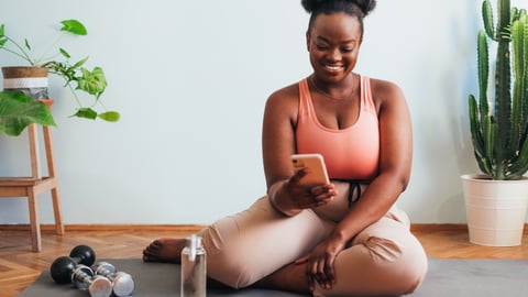 femme noire assise sur un tapis de yoga