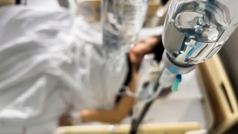 Un patient avec une perfusion intraveineuse dans un lit à l'hôpital. 