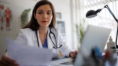 Une médecin, entre sa paperasse et son ordinateur.
