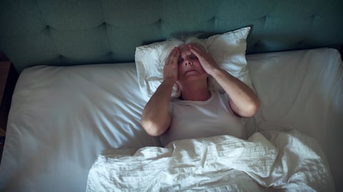Une personne âgée fait de l'insomnie dans son lit.