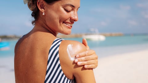 Une femme s'applique de la crème solaire à la plage