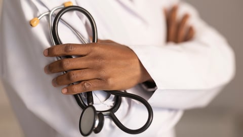 Un médecin tient un stéthoscope en ayant les bras croisés.