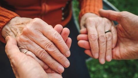 Une personne aînée tient les mains d'une aidante