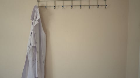 Une blouse blanche / un sarrau accroché à un porte-manteau