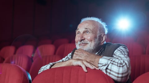 Un homme âgé sourit dans une salle de cinéma