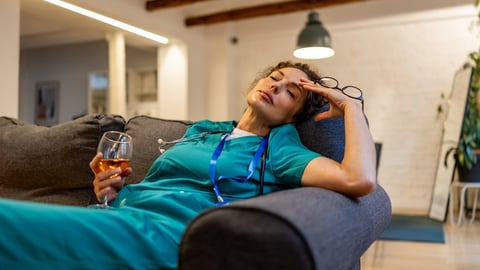 Une femme médecin fatiguée tient dans sa main un verre d'alcool