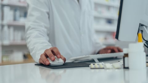 Les mains d'un pharmacien sur un clavier et une souris d'ordinateur