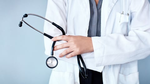 Une femme médecin tient son stéthoscope les bras croisés.