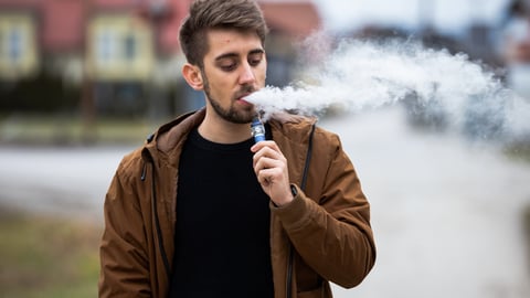Un jeune homme vapote une cigarette électronique
