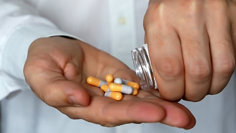 Les mains d'un médecin ou d'un pharmacien versant des capsules de médicaments