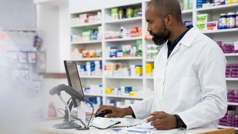 Un pharmacien noir travaille sur son ordinateur au comptoir