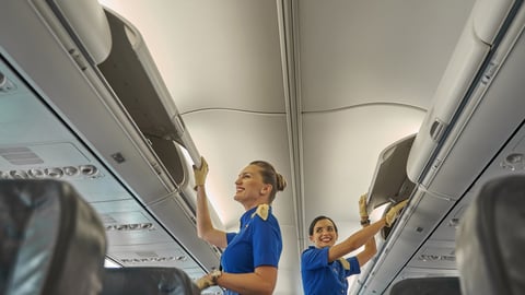 Deux hôtesses de l'air rangent des bagages dans les compartiments de l'avion.