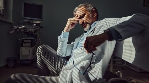 Un médecin épuisé se tient la tête dans la main