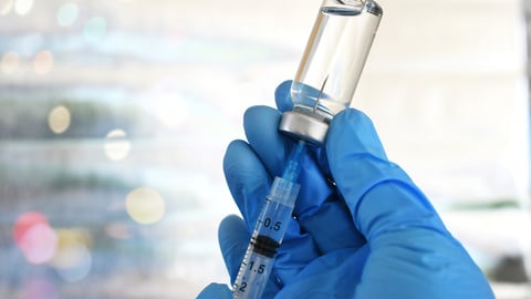 Les mains d'un professionnel de la santé en train de préparer une seringue de vaccin.