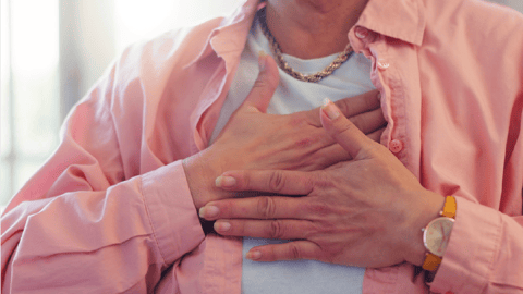 Une personne a mis ses mains sur sa poitrine pour représenter un. essoufflement, une angoisse ou un problème cardiaque.