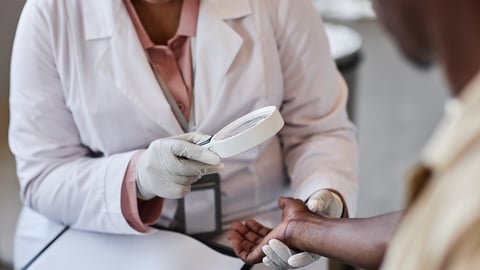 Une pharmacienne réalise un examen dermatologique sur un patient à la peau foncée