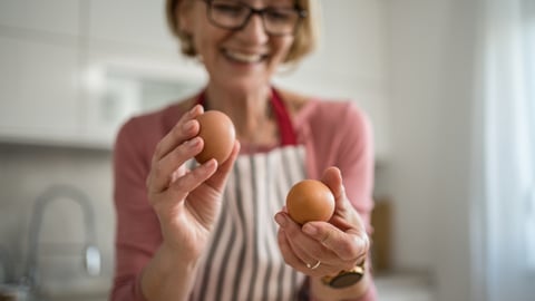 Une femme âgée tient des oeufs dans ses mains