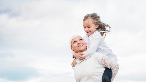 A woman with cancer is  next to her daughter. A girl is hugging a woman happy; Shutterstock ID 1024149976