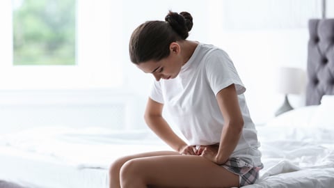 Young woman suffering from menstrual cramps at home. Gynecology; Shutterstock ID 1150901036