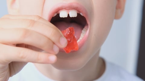 boy, kid holds in his mouth and eats gelatinous sweets, gummy bear, concept of children's delicacy, healthy and unhealthy food, halal food; Shutterstock ID 1793069470